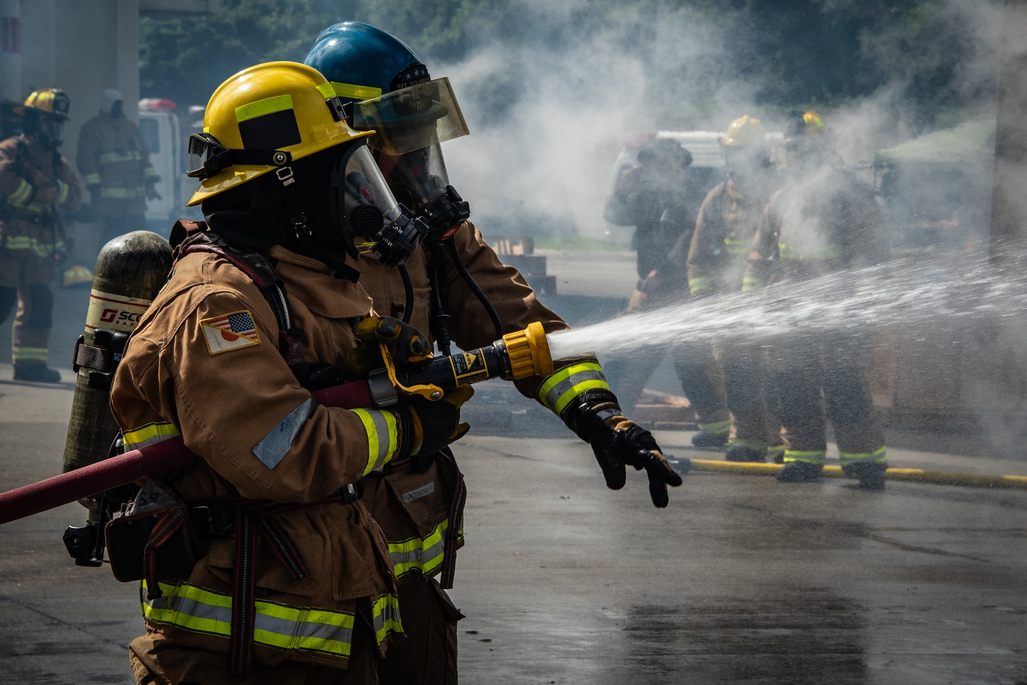 U.S. Marine firefighters assigned to the Headquarters and Headquarters Squadron, Marine Corps Air Station Futenma, train on extinguishing a simulated aircraft fire during a live fire training event at Camp Hansen, Japan, June 12, 2025. The hands-on guidance allows participants to refine nozzle control and fire stream placement in real-time. (U.S. Air National Guard photo by Staff Sgt. Jesse Hanson)