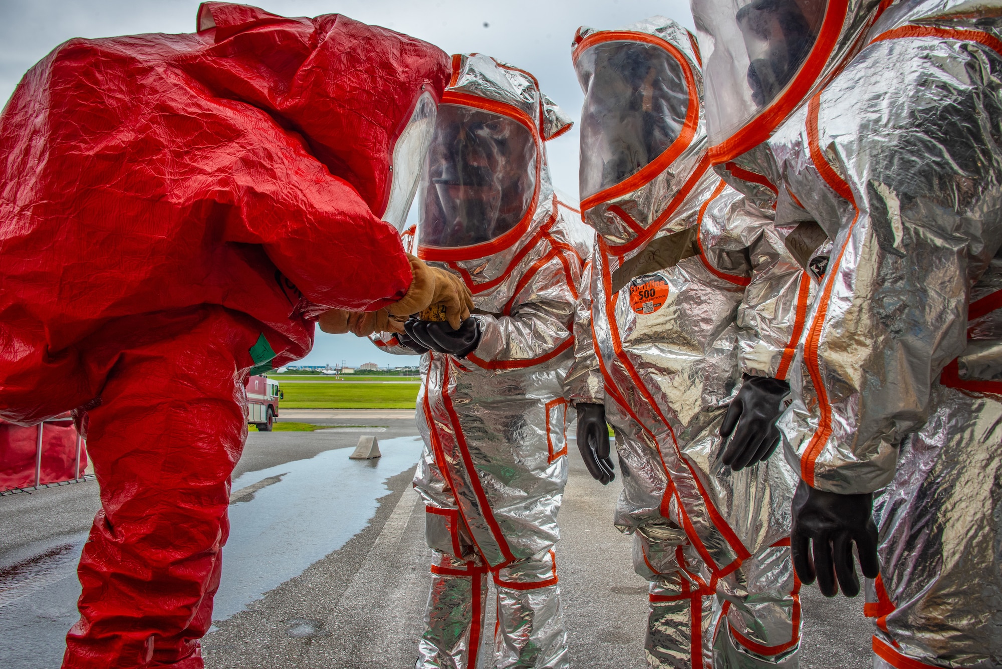 Airman 1st Class Nicholas Garcia, 18th Civil Engineer Squadron, fire and emergency services, passes off a tool during a joint hazardous materials recertification course at Kadena Air Base, Japan, June 18, 2025. Effective teamwork is essential during HAZMAT responses where timing and communication can prevent escalation. (U.S. Air National Guard photo by Staff Sgt. Jesse Hanson)