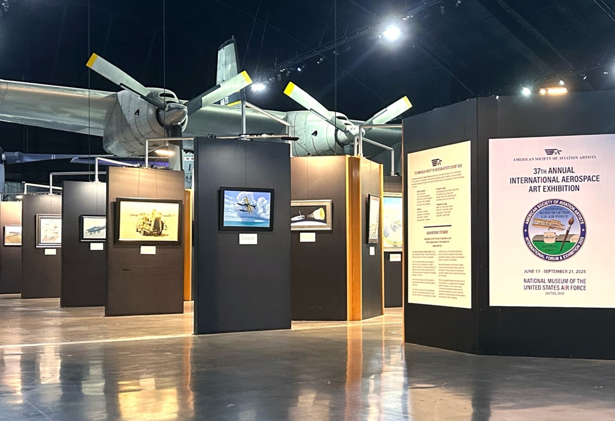 a group of tall black panels showcase artwork with large aircraft in the background