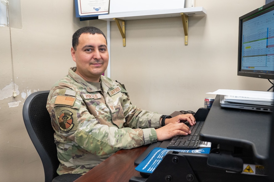 An Airman poses for a photo in front of a computer.