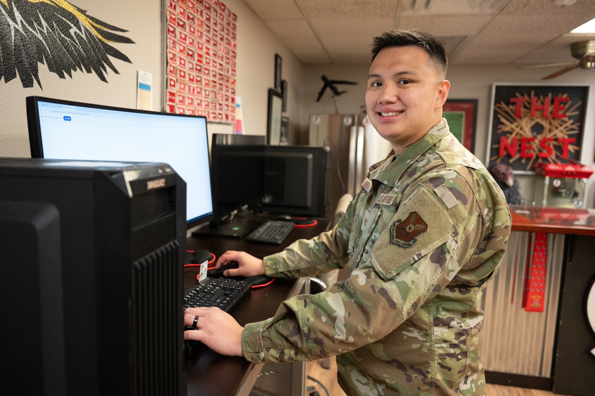 An Airman poses for a photo in front of a computer.