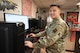 An Airman poses for a photo in front of a computer.