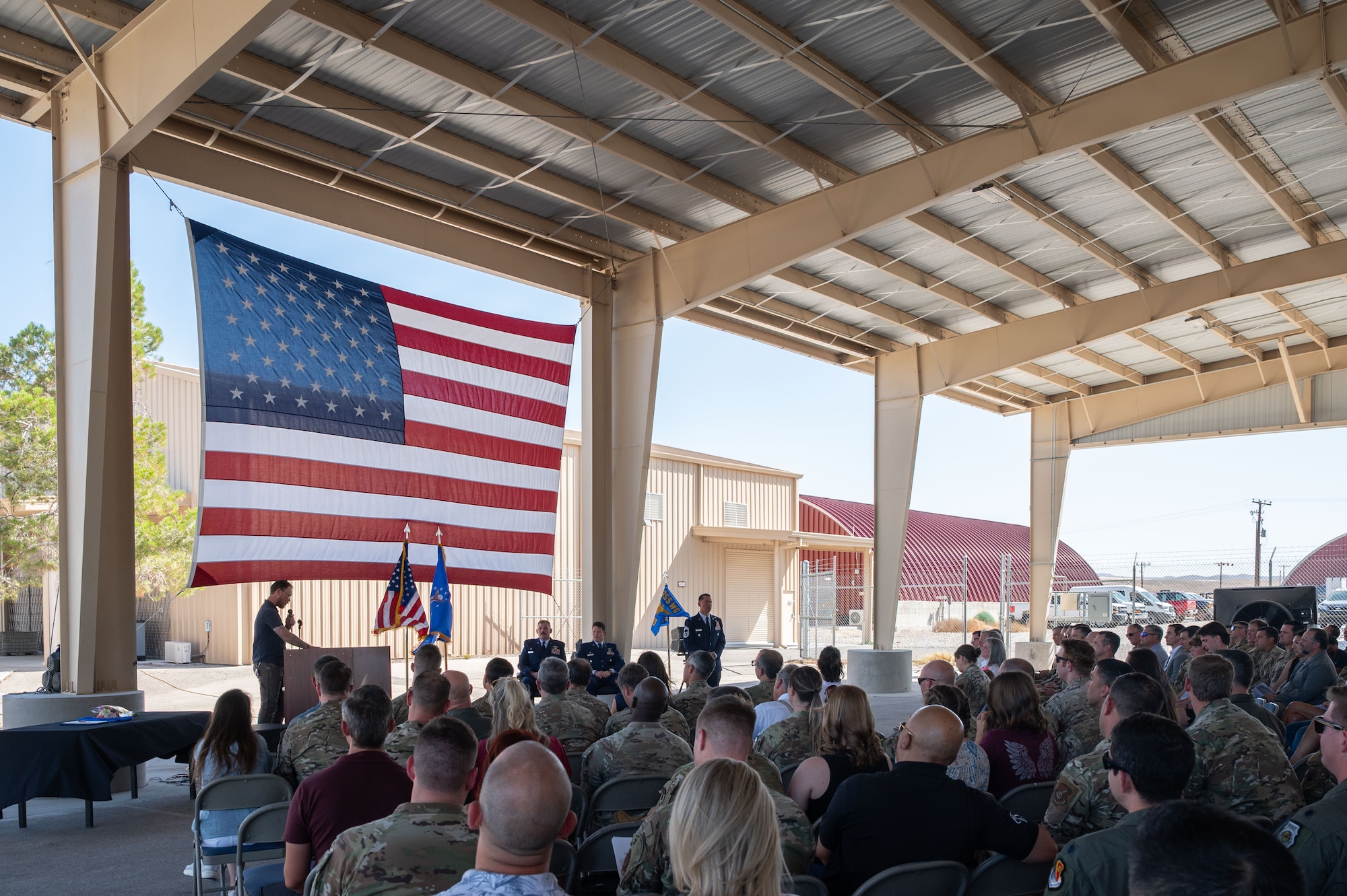 Airmen and guests listen as George Tinseth, 355th Wing historian, delivers a speech highlighting the history and accomplishments of the 58th Rescue Squadron (RQS) during its inactivation ceremony at Nellis Air Force Base, Nevada, June 17, 2025.