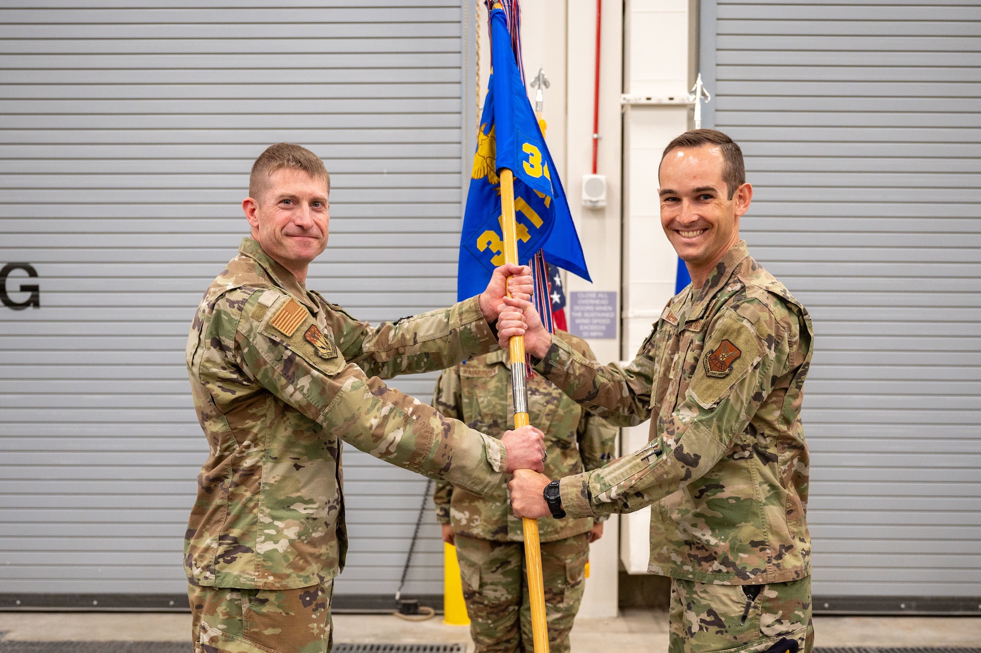Two airmen holding onto a guidon