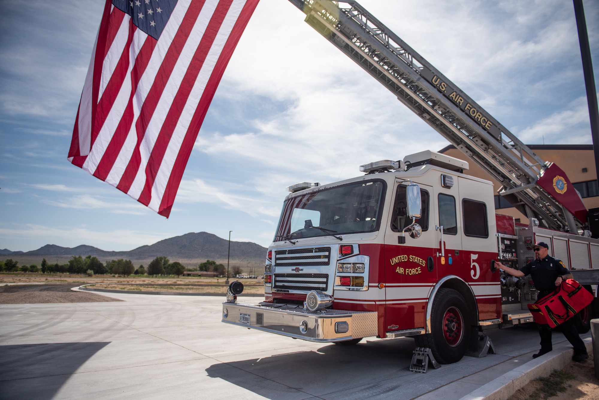 group of civilian and military members applaud after cutting ribbon in front of fire truck