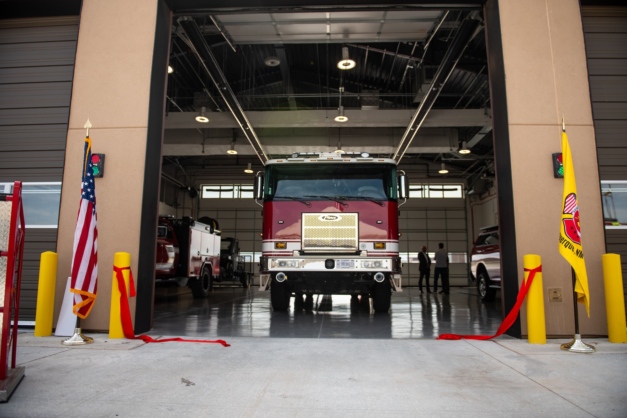 group of civilian and military members applaud after cutting ribbon in front of fire truck