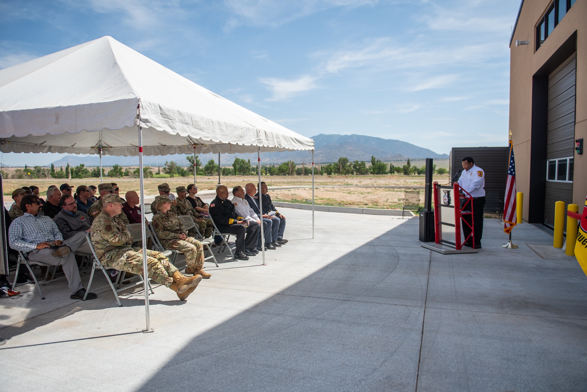 group of civilian and military members applaud after cutting ribbon in front of fire truck