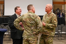 Military members and civilians interact during an honorary commander induction ceremony.