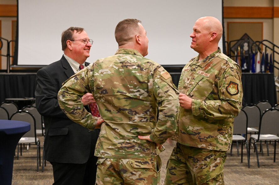 Military members and civilians interact during an honorary commander induction ceremony.