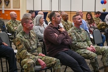 Military members and civilians interact during an honorary commander induction ceremony.