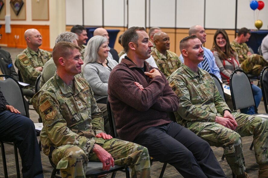 Military members and civilians interact during an honorary commander induction ceremony.