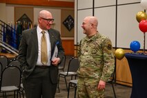 Military members and civilians interact during an honorary commander induction ceremony.