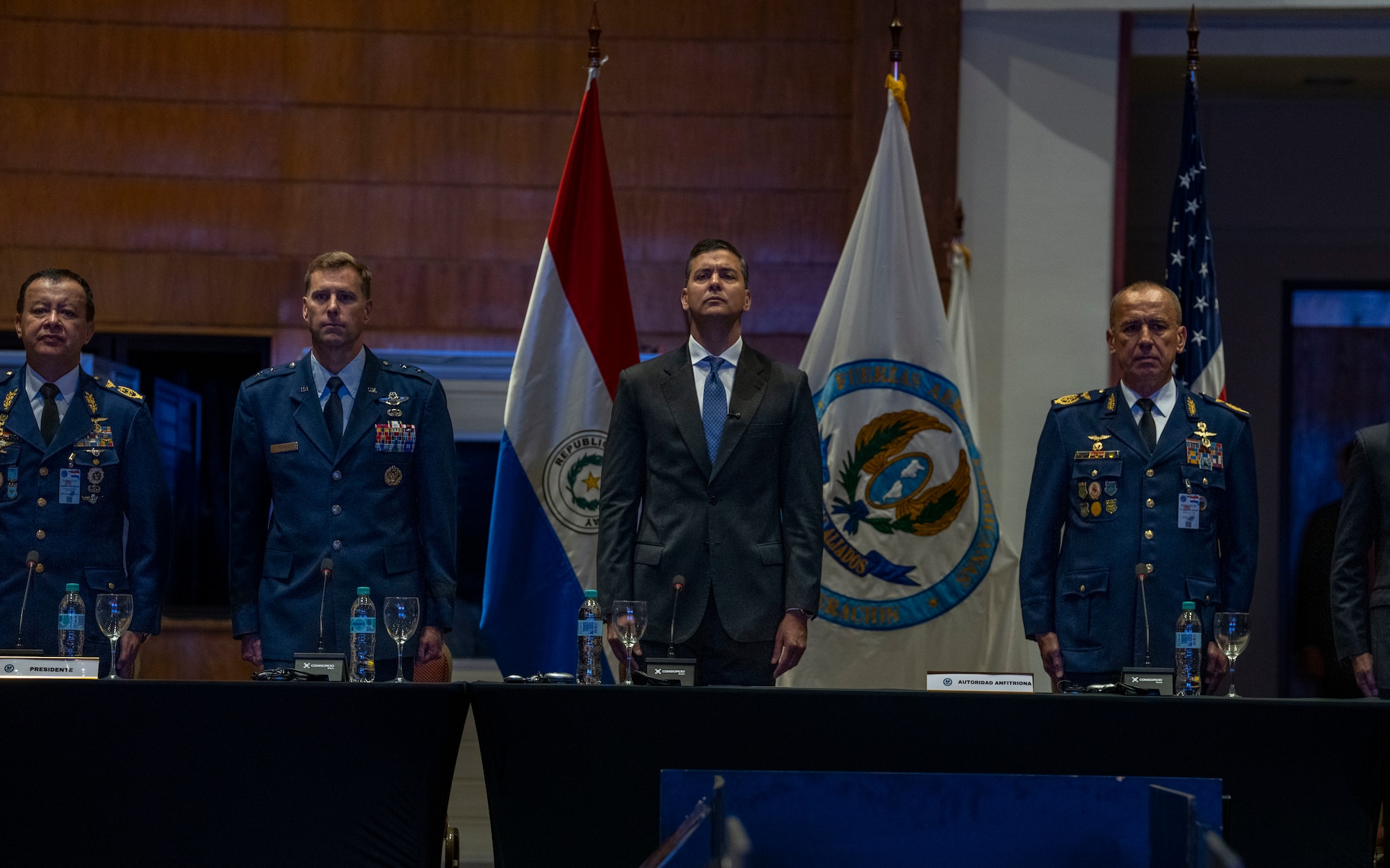 U.S. Air Force Maj. Gen. David Mineau, Air Forces Southern commander, (left center), and  Santiago Peña, President of the Republic of Paraguay, (right center), stand at attention during the national anthems of the U.S. and Paragray during the 65th Conference of the American Air Chiefs (CONJEFAMER) meeting in Asuncion, Paraguay, June 18, 2025. Co-hosted by Paraguayan and the U.S. Air Forces, CONJEFAMER brought together senior air force leaders and representatives from 21 nations to discuss the collective readiness needs of the Western Hemisphere, align on shared goals and lay the groundwork for future joint exercises. (U.S. Air Force photo by Andrea Jenkins)