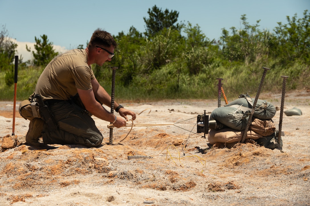 U.S. Marine Corps Sgt. Joshua Upright, an explosive ordnance disposal technician with Marine Corps Base Camp Butler, ties a rocket wrench to a spike during an EOD training exercise on Camp Hansen, Okinawa, Japan, June 17, 2025. A rocket wrench is a specialized tool that uses .50-caliber blank rounds to safely remove the fuse from explosive ordnance. The purpose of this exercise was to help enhance the EOD section’s ability to conduct inerting and exploitation operations. Upright is a native of Florida. (U.S. Marine Corps photo by Lance Cpl. Joseph Kreis)