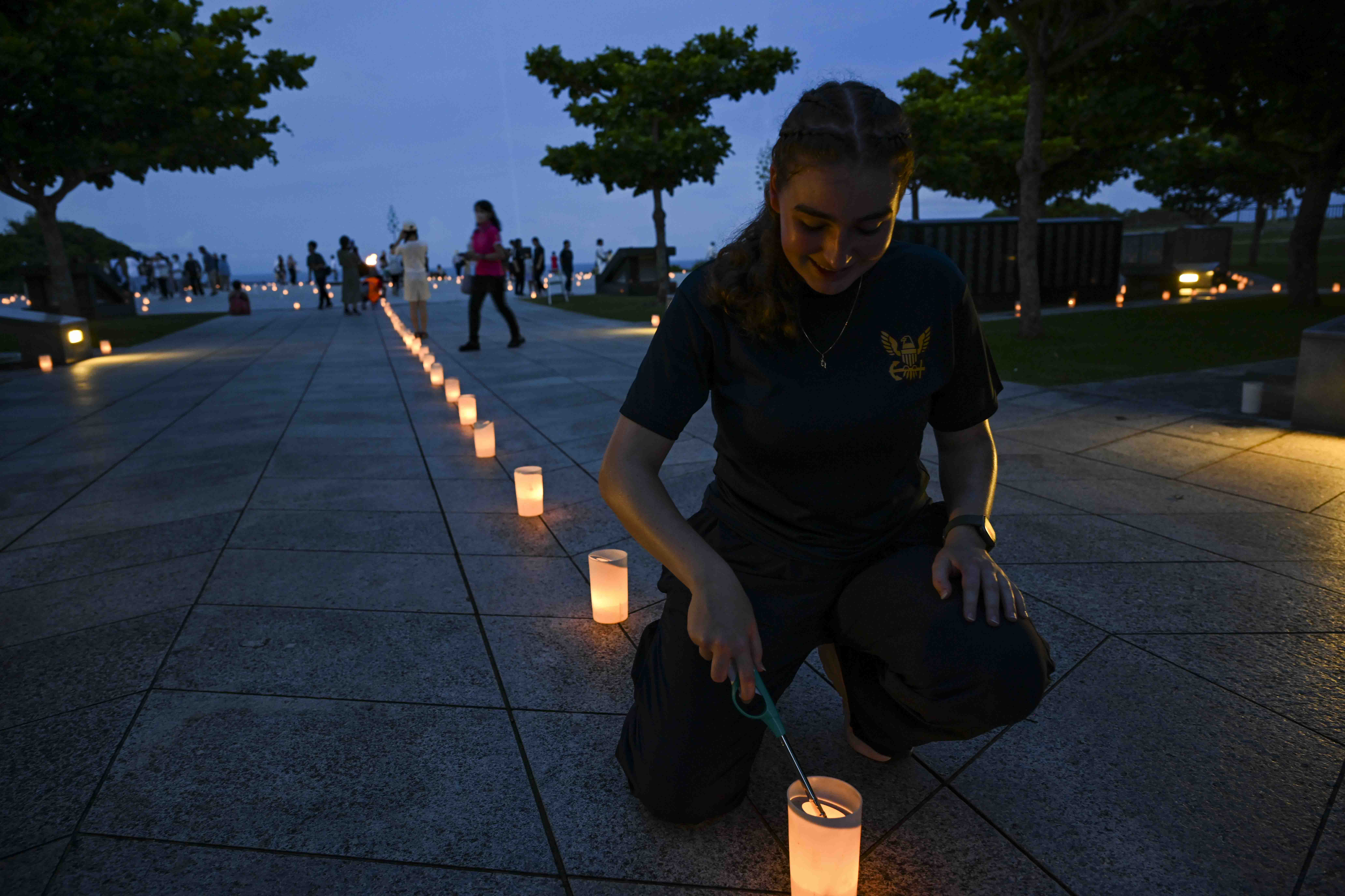 Hospital Corpsman 3rd Class Bianca Cureau, from Austin, Texas, assigned to U.S. Naval Hospital Okinawa, lights a candle during a volunteer candle lighting event at Peace Memorial Park in Itoman, Okinawa, Japan, June 22, 2025.