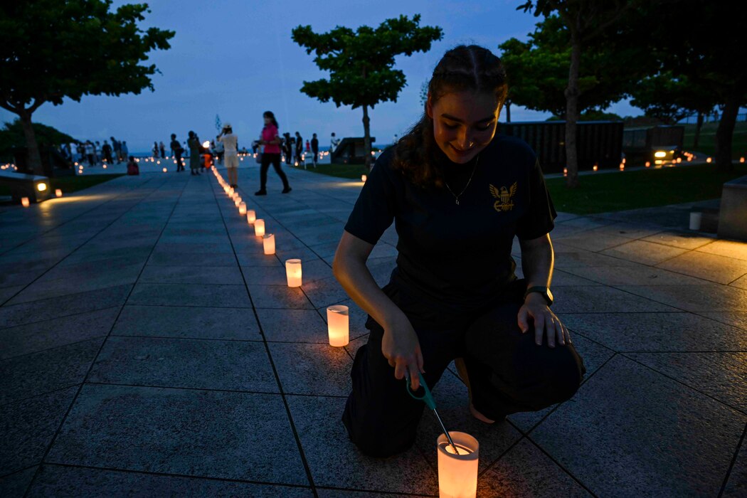 Hospital Corpsman 3rd Class Bianca Cureau, from Austin, Texas, assigned to U.S. Naval Hospital Okinawa, lights a candle during a volunteer candle lighting event at Peace Memorial Park in Itoman, Okinawa, Japan, June 22, 2025.