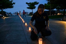 Hospital Corpsman 3rd Class Bianca Cureau, from Austin, Texas, assigned to U.S. Naval Hospital Okinawa, lights a candle during a volunteer candle lighting event at Peace Memorial Park in Itoman, Okinawa, Japan, June 22, 2025.