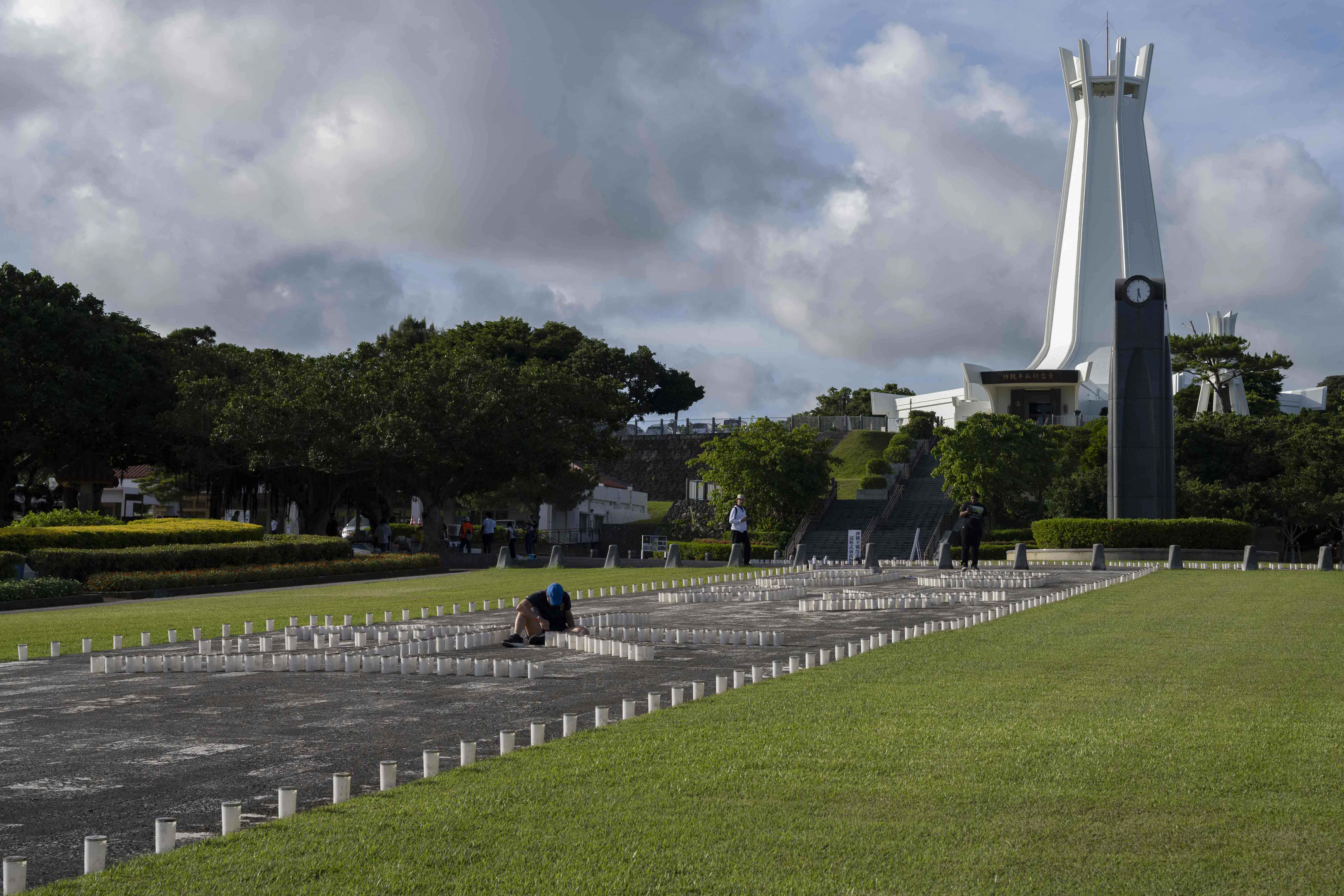 Hospital Corpsman 2nd Class Andrea Mayrose, from Salem, South Dakota, assigned to U.S. Naval Hospital Okinawa, helps light the more than 7,000 candles that illuminate the memorials walls and walk ways at Peace Memorial Park during a volunteer candle lighting event in Itoman, Okinawa, Japan, June 22, 2025.