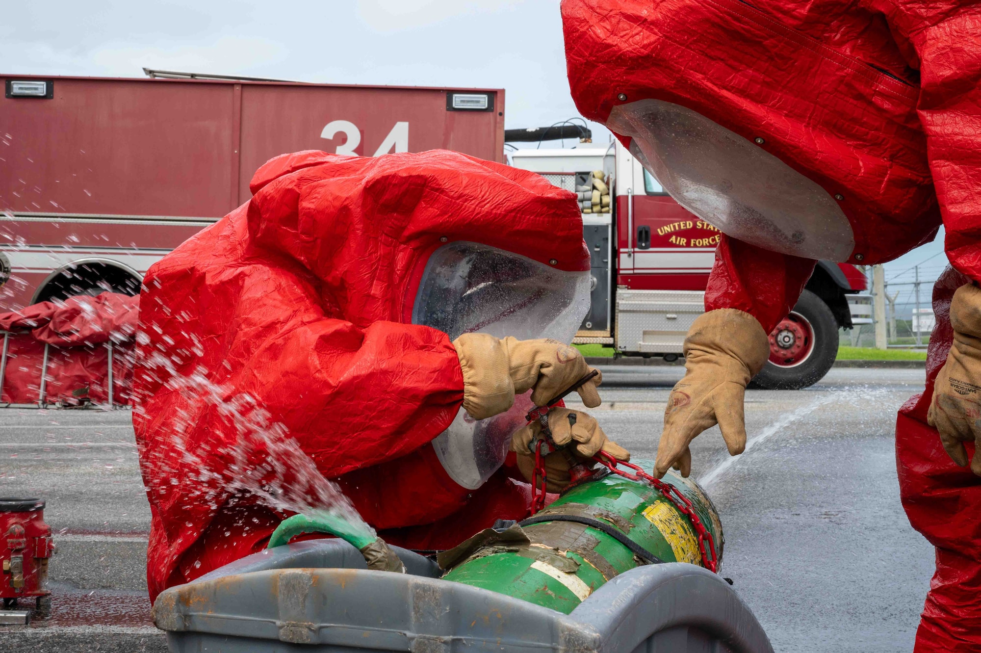 service members in protective suits work together to stop a leak