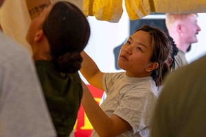 service member helps set up tent