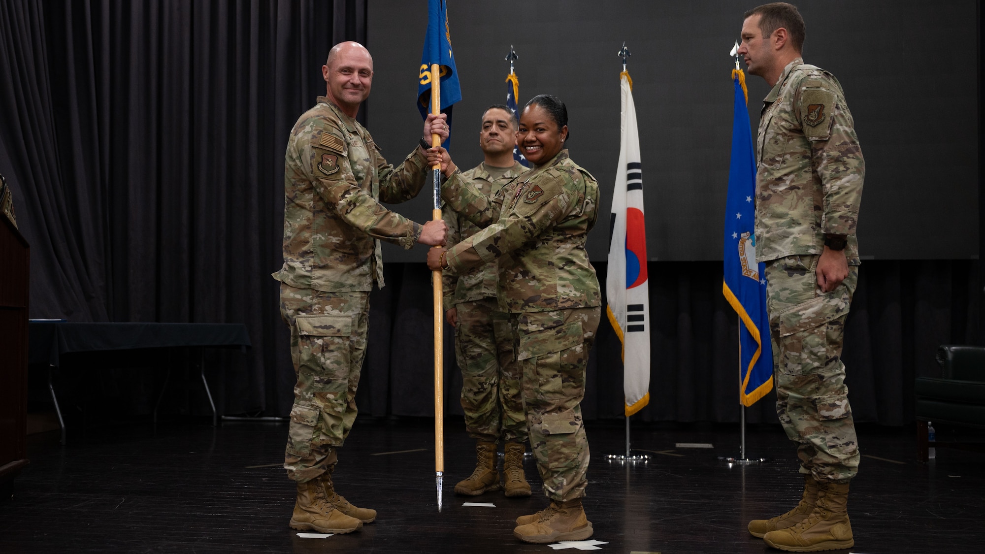 U.S. Air Force Col. Jeff Elliott, left, 51st Mission Support Group commander, receives the guidon from Lt. Col. Annabelle Hill, outgoing 51st Force Support Squadron commander, during a Change of Command ceremony at Osan Air Base, Republic of Korea, June 24, 2025. Hill is responsible for building the framework for the force support squadron of the future in support of twenty-first century Airmen, Guardians, and their families. (U.S. Air Force photo by Senior Airman Rome Bowermaster)