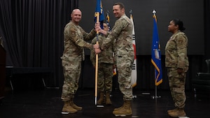 U.S. Air Force Col. Jeff Elliott, left, 51st Mission Support Group commander,  passes the guidon to Lt. Col. Edmund Ward, right, incoming 51st Force Support Squadron commander, during a Change of Command ceremony at Osan Air Base, Republic of Korea, June 24, 2025. Prior to assuming command, Ward led the 647th Force Support Squadron as the commander and the Deputy Department Head, Joint Base Warfighter and Family Services, Hickam Air Force Base, Hawaii. (U.S. Air Force photo by Senior Airman Rome Bowermaster)
