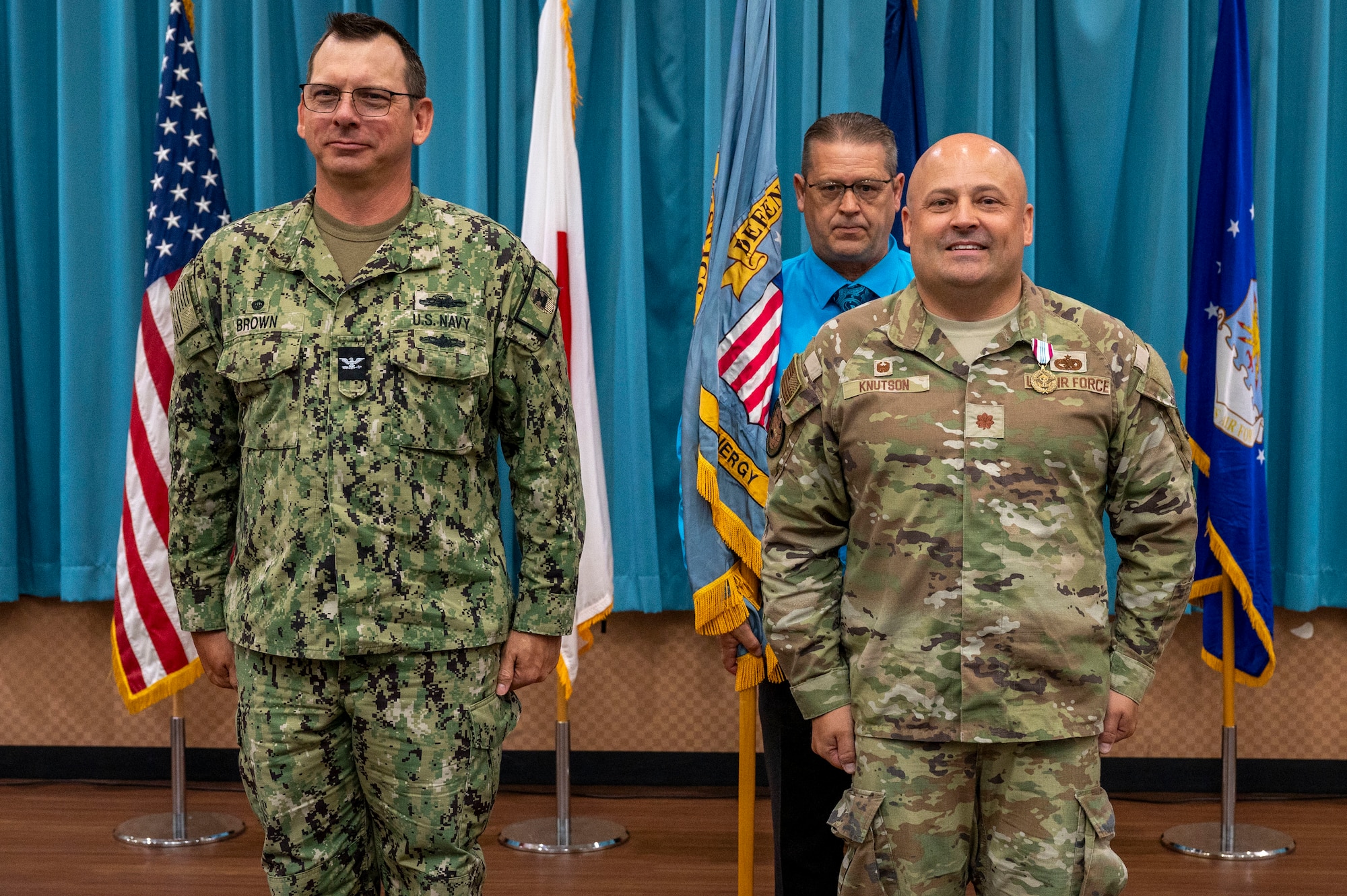 U.S. Navy Capt. Patrick Brown, Defense Logistics Agency Indo-Pacific commander, left, prepares to receive the guidon from U.S. Air Force Maj. Kevin Knutson, DLA Energy Okinawa outgoing commander, right, during a change of command ceremony at Kadena Air Base, Japan, June 18, 2025.