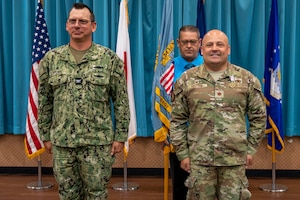 U.S. Navy Capt. Patrick Brown, Defense Logistics Agency Indo-Pacific commander, left, prepares to receive the guidon from U.S. Air Force Maj. Kevin Knutson, DLA Energy Okinawa outgoing commander, right, during a change of command ceremony at Kadena Air Base, Japan, June 18, 2025.