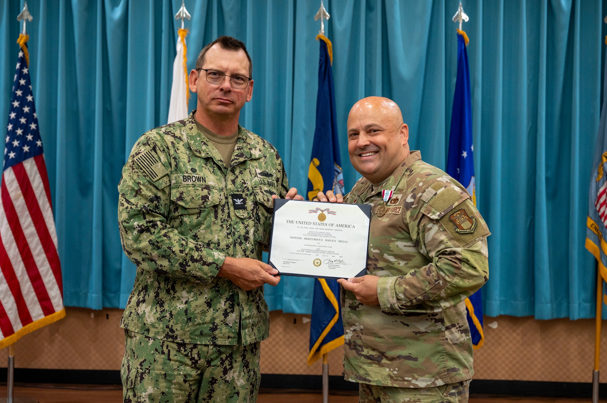 U.S. Navy Capt. Patrick Brown, Defense Logistics Agency Indo-Pacific commander, left, presents a meritorious service medal to U.S. Air Force Maj. Kevin Knutson, Defense Logistics Agency Energy Okinawa outgoing commander, right, during a change of command ceremony at Kadena Air Base, Japan, June 18, 2025.
