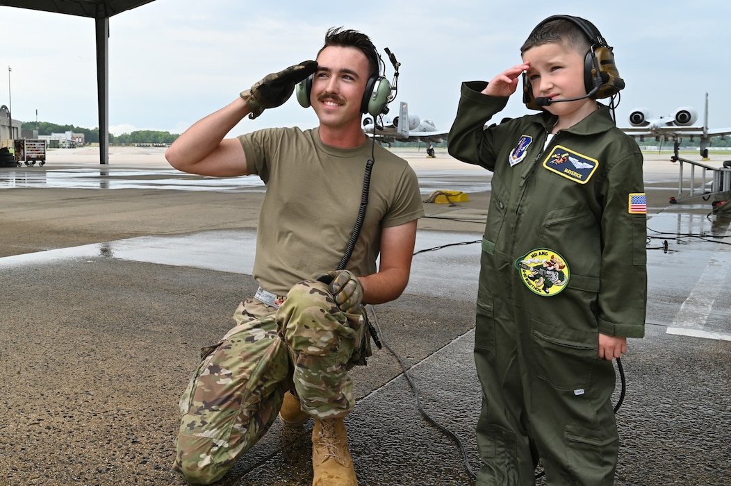 Maryland Air National Guard Senior Airman Jacob Kosubinsky (left), a crew chief assigned to the 175th Maintenance Squadron, salutes on the flight line with Maverick Bell (right) at Warfield Air National Guard Base at Martin State Airport, Maryland, June 7, 2025. Bell and his family attended "Pilot For a Day," facilitated by the Gold in Fight Foundation, which invites children and families from the local community who have catastrophic illnesses to spend the day with pilots. (U.S. Air National Guard Photo by Staff Sgt. Laura Virtue)