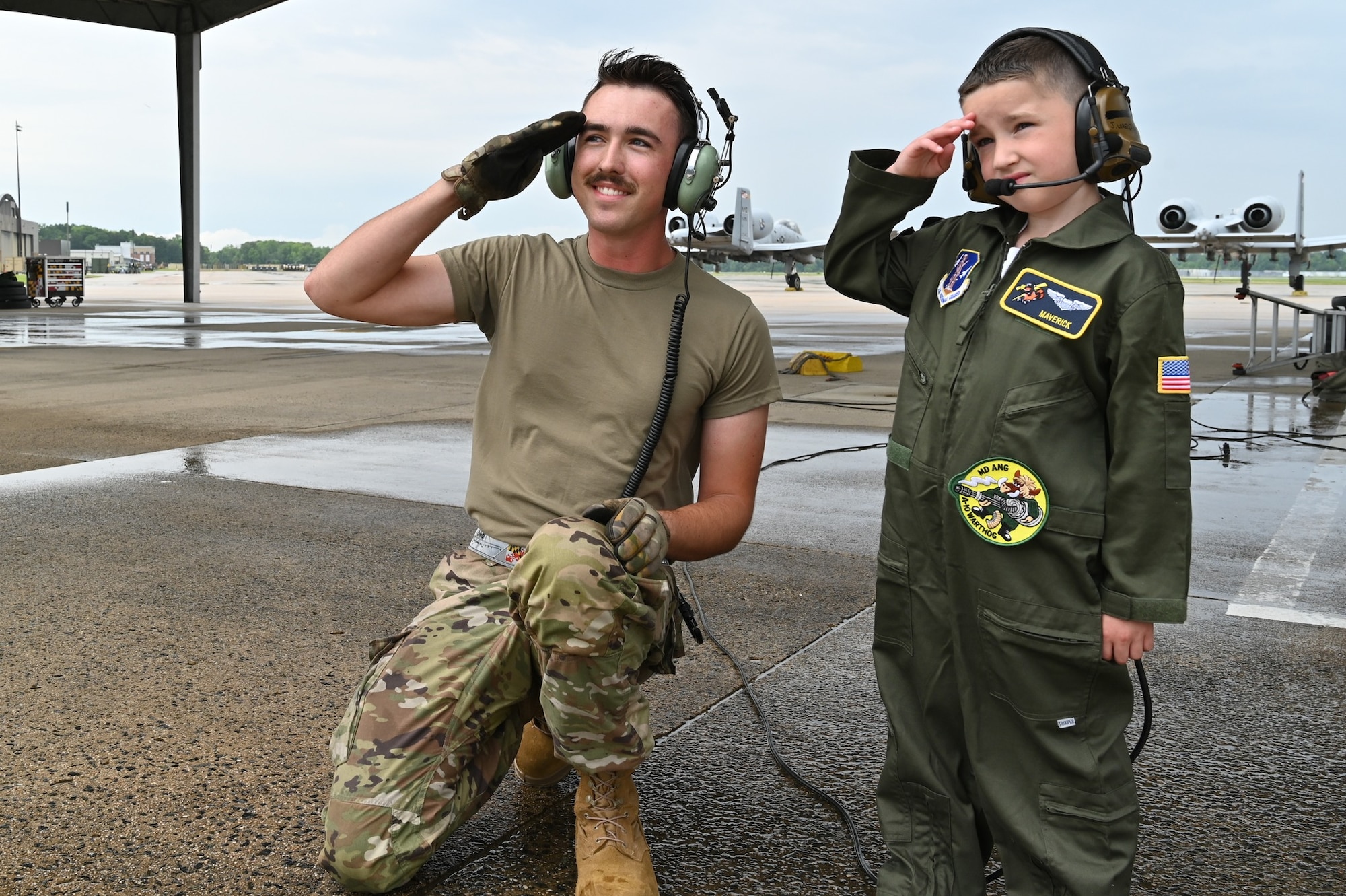 Maryland Air National Guard Senior Airman Jacob Kosubinsky (left), a crew chief assigned to the 175th Maintenance Squadron, salutes on the flight line with Maverick Bell (right) at Warfield Air National Guard Base at Martin State Airport, Maryland, June 7, 2025. Bell and his family attended "Pilot For a Day," facilitated by the Gold in Fight Foundation, which invites children and families from the local community who have catastrophic illnesses to spend the day with pilots. (U.S. Air National Guard Photo by Staff Sgt. Laura Virtue)