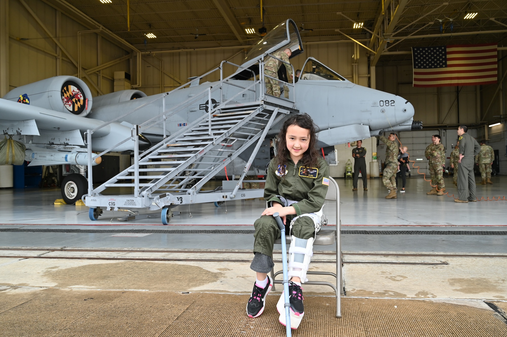 Elena LeMoine, an honorary Pilot for a Day, sits in front of a Maryland Air National Guard A-10C Thunderbolt II static display at Warfield Air National Guard Base at Martin State Airport, Maryland, June 7, 2025. LeMoine and her family attended "Pilot For a Day," facilitated by the Gold in Fight Foundation, which invites children and families from the local community who have catastrophic illnesses to spend the day with pilots. (U.S. Air National Guard Photo by Staff Sgt. Laura Virtue)