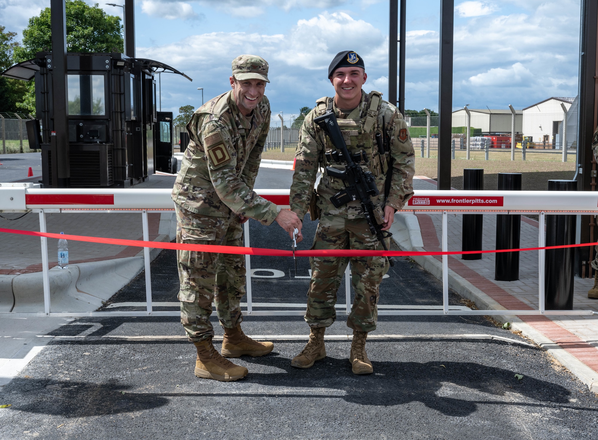 U.S. Air Force Col. Ryan Garlow, left, 100th Air Refueling Wing commander, and Airman Jonah Kniss, 100th Security Forces Squadron response force member, pose for a photo during the new gate reveal at RAF Mildenhall, England, June 24, 2025.