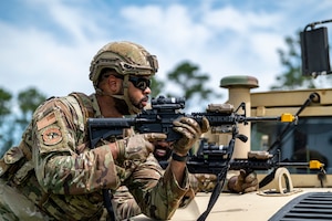 Airmen with the 910th Security Forces Squadron, Youngstown Air Reserve Station, Ohio, take aim using a vehicle as cover at Moody Air Force Base, Georgia, June 20, 2025. Airmen practiced overwatch and defensive tactics while concealed in natural terrain, simulating real-world combat scenarios during opposing force drills in a field environment. (U.S. Air Force photo by Senior Airman Leonid Soubbotine)
