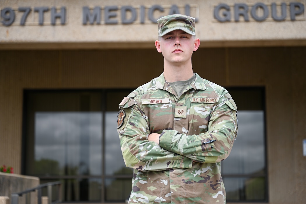U.S. Air Force Staff. Sgt. Jack Brown, 97th Healthcare Operations Squadron TRICARE operations and patient administration non-commissioned officer in charge, stands in front of the 97th Medical Group Building at Altus Air Force Base, Oklahoma, May 28,2025. Brown was recently promoted to the rank of staff sergeant within five years of service. (U.S. Air Force photo by Airman 1st Class Nathan Langston)