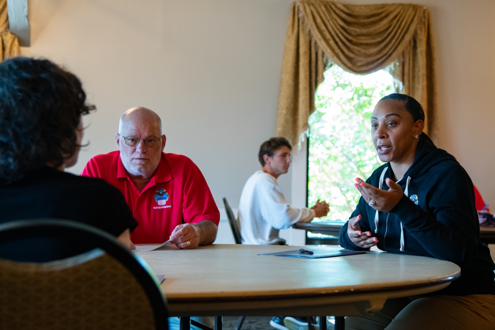 A man and woman sit at a table looking across the table at another person.