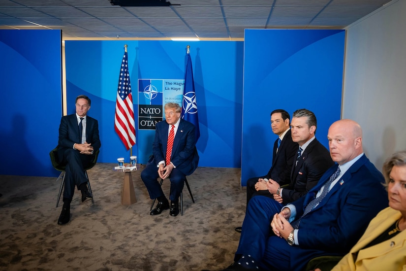 The NATO secretary general and U.S. president sit in chairs for a briefing.