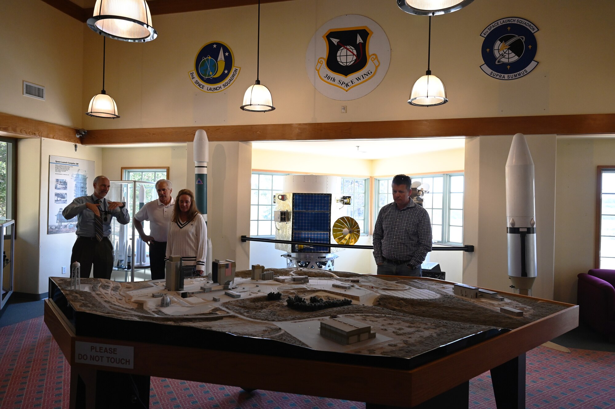 a group of people stand in a room and look at a model of a missile launch facility