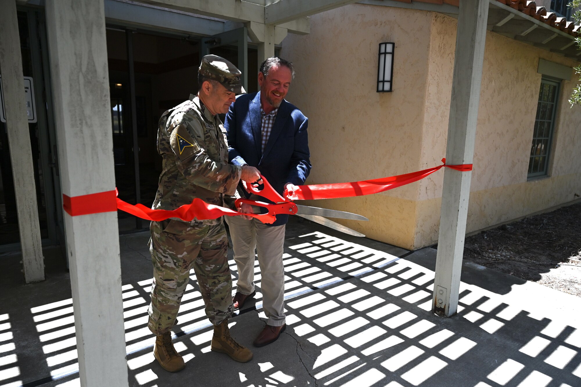 a man cuts a red ribbon with large red scissors