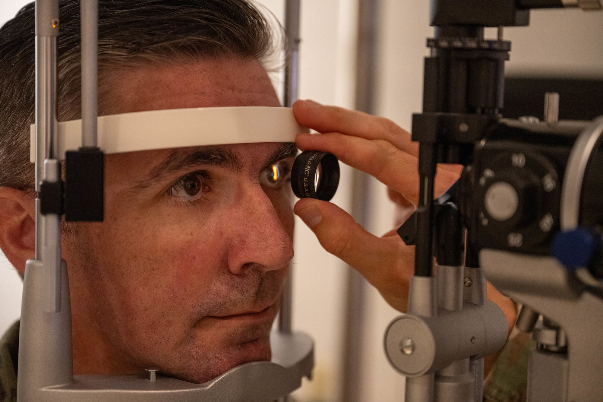 A patient in the optometry office on Joint Base Pearl Harbor-Hickam, Hawaii, gets his eye examined by a doctor.
