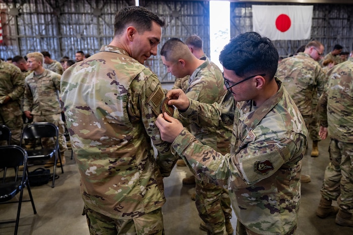U.S. Air Force Airmen assigned to the newly formed 35th Munitions Squadron apply the squadron's patch to their uniforms during an activation ceremony at Misawa Air Base, Japan, June 17, 2025.