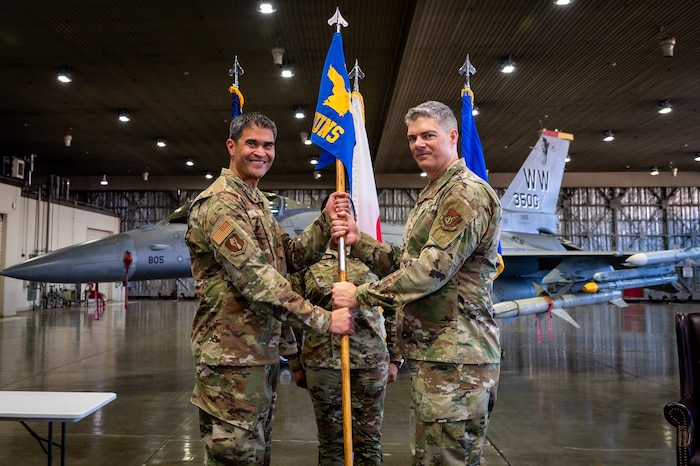 U.S. Air Force Col. Bryan Wong, 35th Maintenance Group commander, hands Maj. Steven Bayne, 35th Munitions Squadron (MUNS) commander, the newly formed 35th MUNS guidon during an activation ceremony at Misawa Air Base, Japan, June 17, 2025.