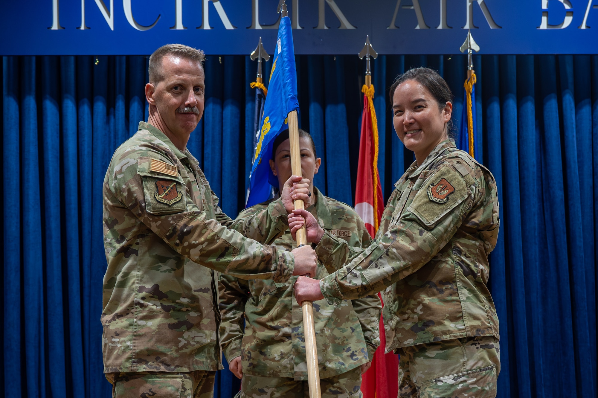 U.S. Air Force Col. Christian Smith, commander of the 39th Medical Group, passes the guidon to Lt. Col. Michelle Reneau, 39th Operational Medical Readiness Squadron incoming commander, during a change of command ceremony at Incirlik Air Base, Turkey, June 10, 2025. The change of command ceremony is a long-standing military tradition that represents the formal transfer of responsibility from one officer to another. (U.S. Air Force photo by Staff Sgt. Koby I. Saunders)