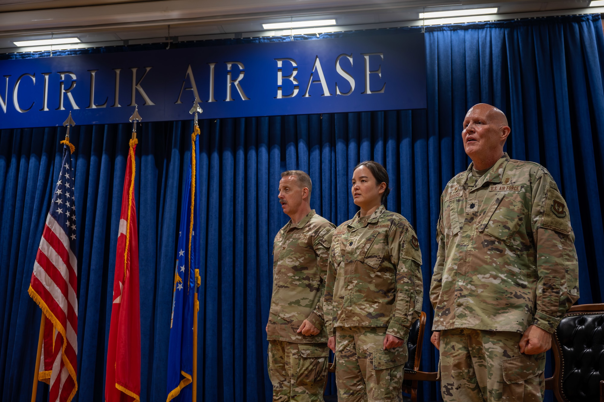 U.S. Air Force Col. Christian Smith, left, commander of the 39th Medical Group,  Lt. Col. Michelle Reneau, commander of the 39th Operational Medical Readiness Squadron, Lt. Col. Richard Odosso, former commander of the 39th Operational Medical Readiness Squadron, right, sing the Air Force song during a change of command ceremony at Incirlik Air Base, Turkey, June 10, 2025. The change of command ceremony is a long-standing military tradition that represents the formal transfer of responsibility from one officer to another. (U.S. Air Force photo by Staff Sgt. Koby I. Saunders)