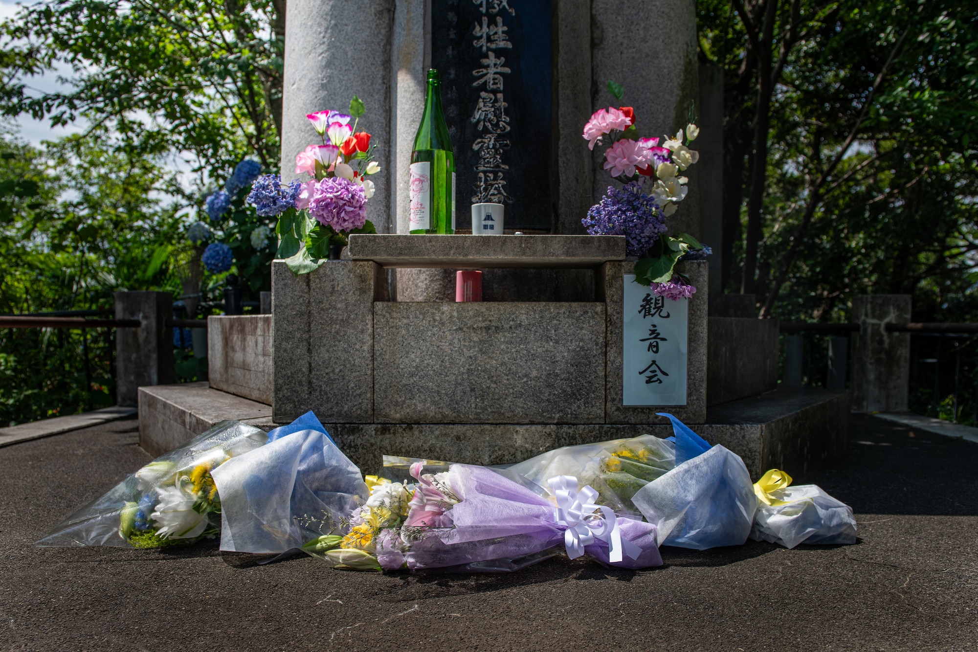 Colorful flowers lay at the foot and on the sides of a stone monument.