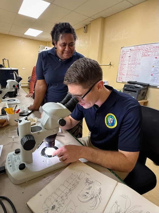 250610-N-RM599-1001 SUVA, Fiji (June 10, 2025) Lt. Corey Day, right, entomologist assigned to Navy Medicine Readiness Training Command, observes mosquito larvae under a microscope at the Fiji Center for Disease Control during Pacific Partnership 2025 in Suva, Fiji, June 10, 2025. Now in its 21st iteration, the Pacific Partnership series is the largest annual multinational humanitarian assistance and disaster management preparedness mission conducted in the Indo-Pacific. Pacific Partnership works collaboratively with host and partner nations to enhance regional interoperability and disaster response capabilities, increase security and stability in the region, and foster new and enduring friendships in the Indo-Pacific. (U.S. Navy photo by Courtesy Asset)