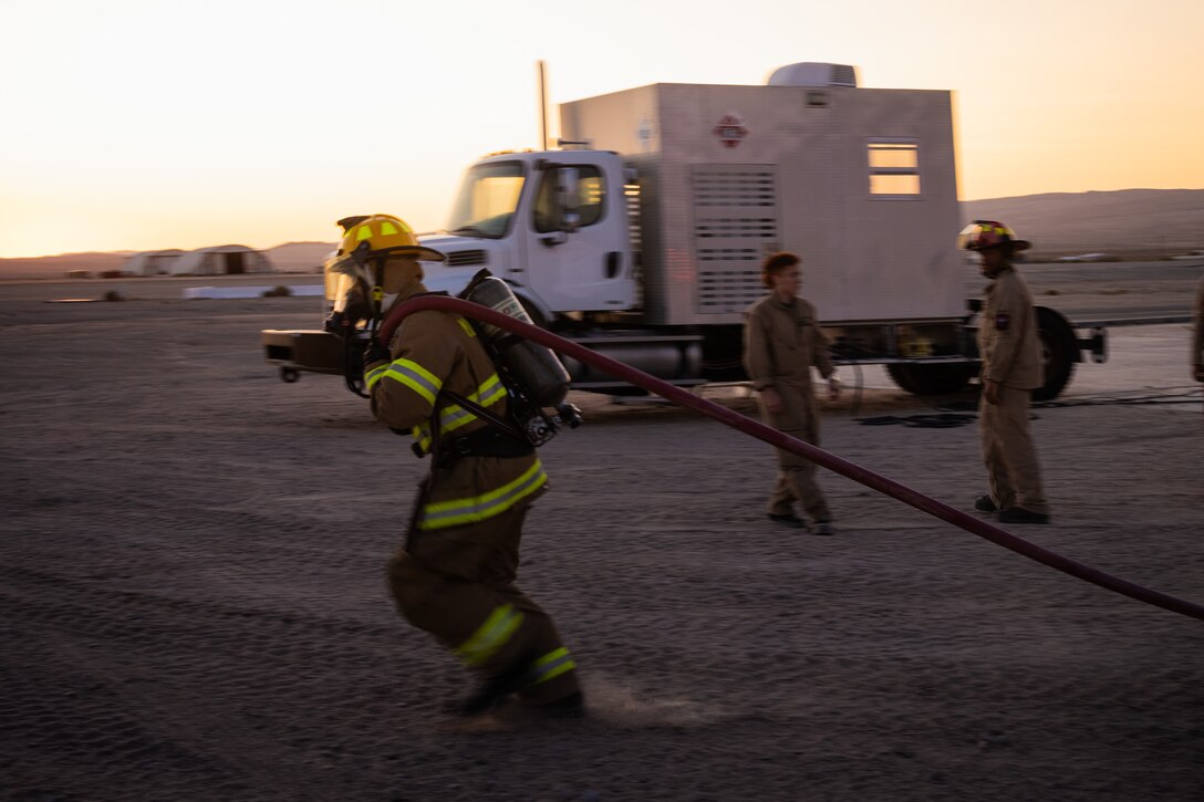 U.S. Marine Corps Lance Cpl. Joseph Vasquez, a firefighter, with Aircraft Rescue and Fire Fighting, Marine Wing Support Squadron 472, 4th Marine Aircraft Wing, pulls a fire hose during a simulated aircraft fire-fighting drill at Integrated Training Exercise 3-25, Marine Corps Air Ground Combat Center, Twentynine Palms, California, June 17, 2025. ITX is a critical Marine Air-Ground Task Force exercise for the Marine Forces Reserve’s training cycle, confirming unit readiness through live-fire and combined-arm integration. (U.S. Marine Corps photo by Lance Cpl. Edward Spears)