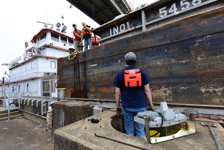 Lock Operator Brandon Hamilton (Forefront) assists deck hands Jan. 31, 2025, with connecting a floating mooring bit at the Wilson Auxiliary Lock on the Tennessee River in Florence, Alabama. U.S. Army Corps of Engineers Nashville District lock operators have been working around the clock since September 2024 to move commerce through the auxiliary lock during an outage of the main lock that required extensive repairs. USACE officials report that the main lock is reopening on or about June 30, 2025. (USACE Photo by Lee Roberts)