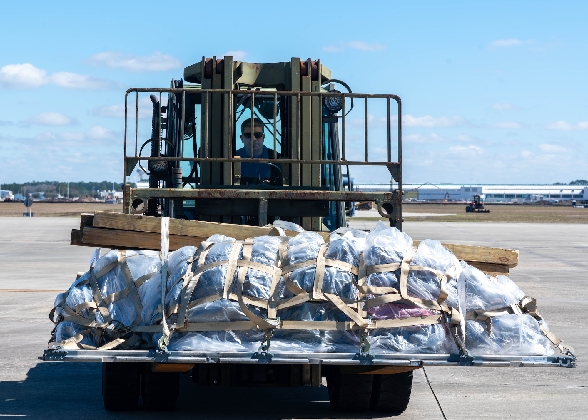 Personnel operating a forklift with palletized luggage.