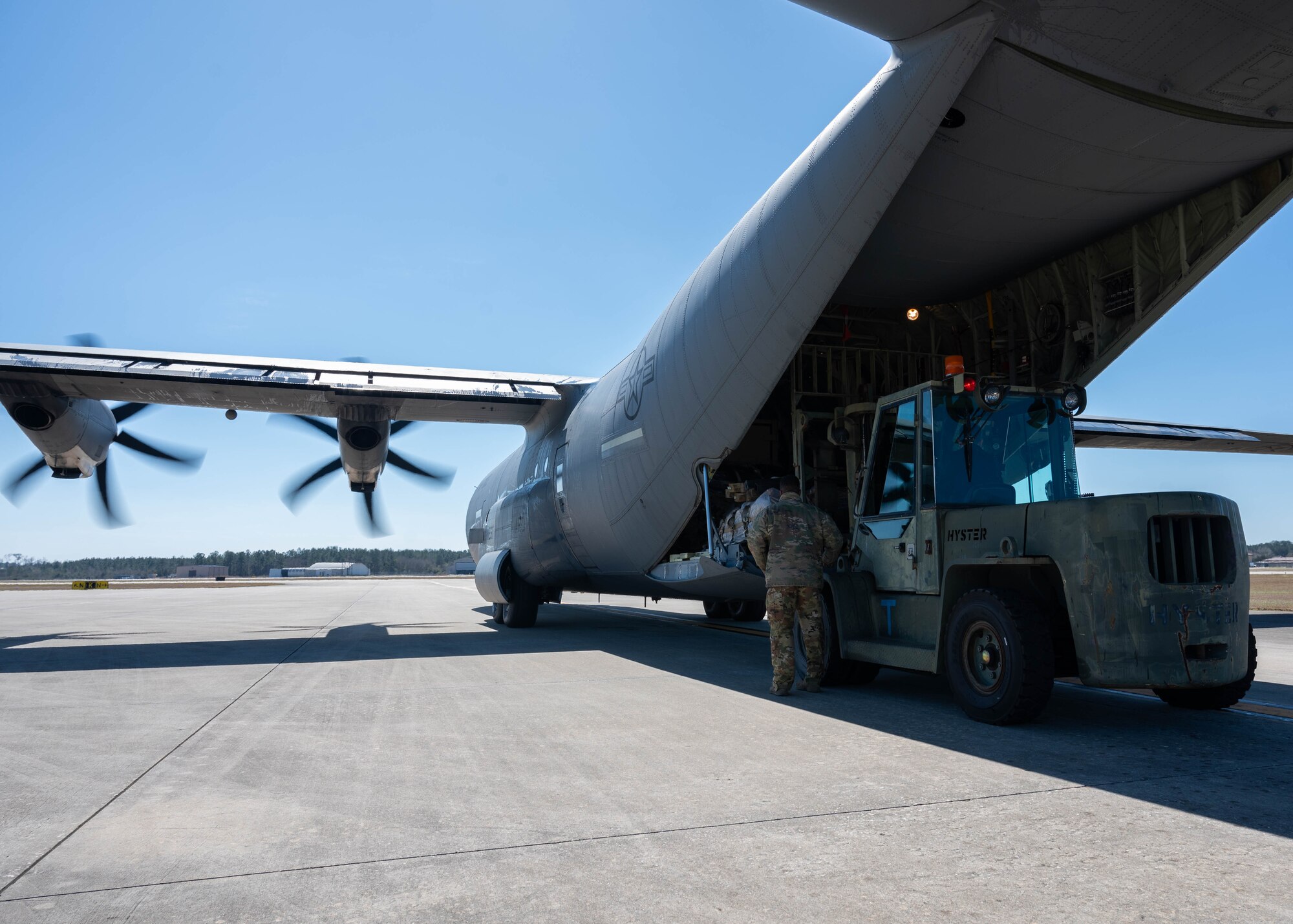 Personnel load a pallet full of gear onto a C-130 Hercules.